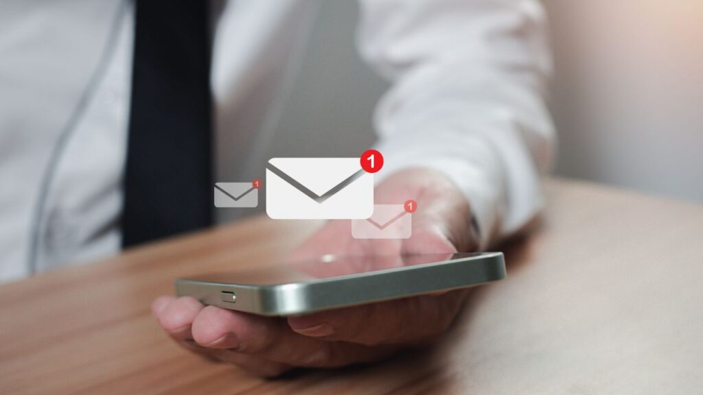 A man holding a smartphone with email Notification icons on the screen 