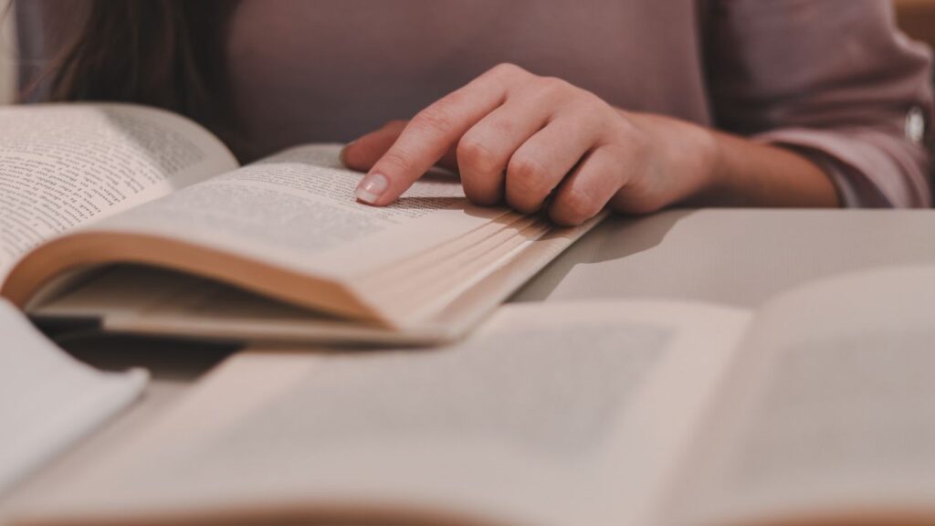 Aesthetic image of A person sitting at a table, engrossed in reading a book.